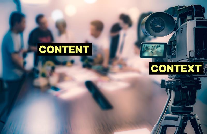 [People meeting in a conference room viewed through a video camera. The people and the room is labeled CONTENT and the camera is labeled CONTEXT]